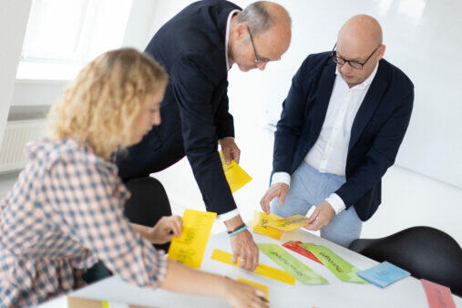 En gruppe forretningsfolk, der engagerer sig i organisationsudviklingsaktiviteter, mens de samarbejder om den regenerative projektlederuddannelse