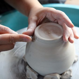 En person laver en lerkrukke på et keramikhjul.