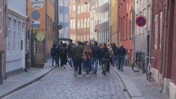 En gruppe mennesker, der går ned ad en brostensbelagt gade, viser lederevner og fremmer organisationsudvikling.