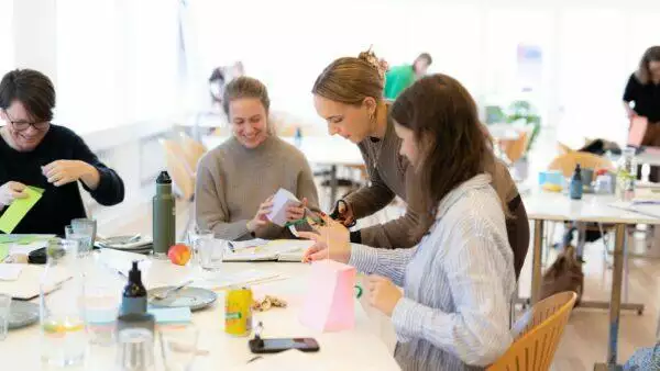 En gruppe mennesker engageret i frisætte og organisationsudvikling ved et bord, ledet af en ekspert i ledelse.