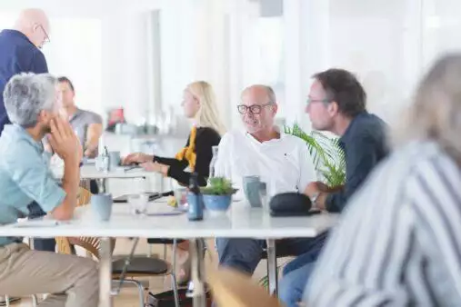 En gruppe mennesker sidder omkring et bord på et kontor.