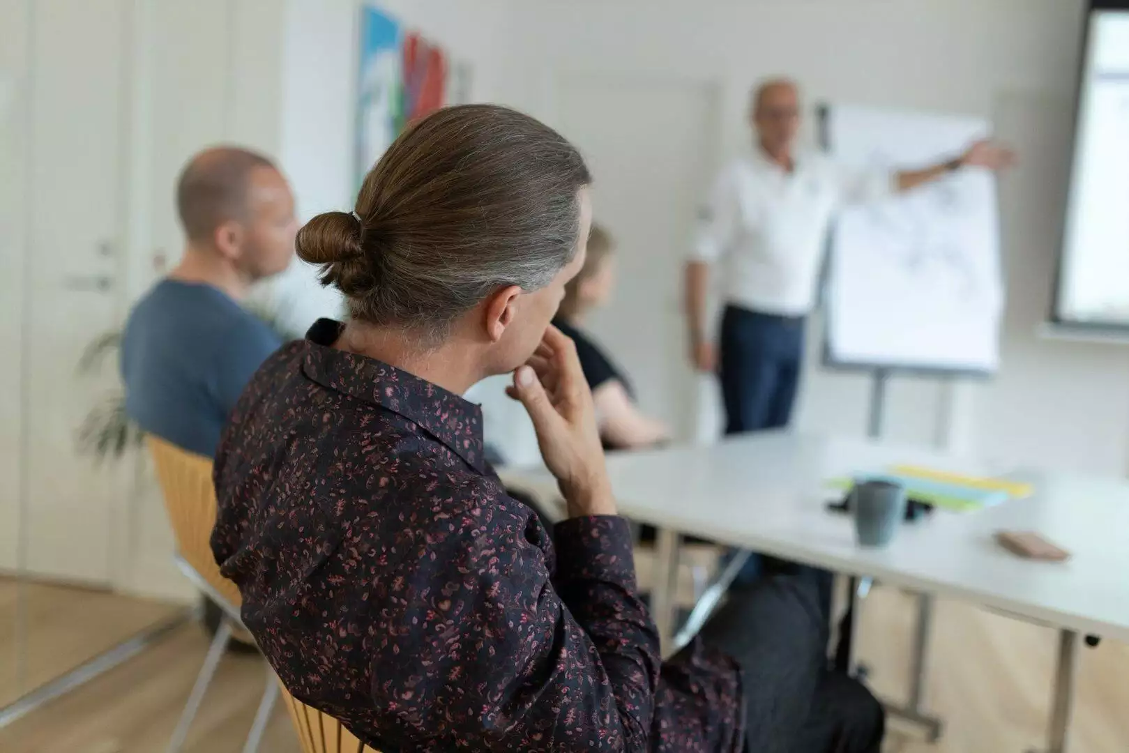 En gruppe mennesker engageret i et ledelsesmøde, der diskuterer organisationsudviklingsstrategier.