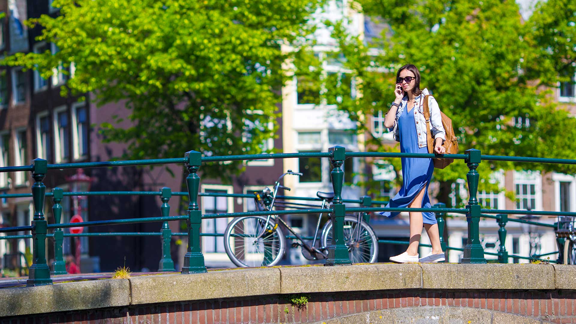 En kvinde står på en bro og taler i sin mobiltelefon.