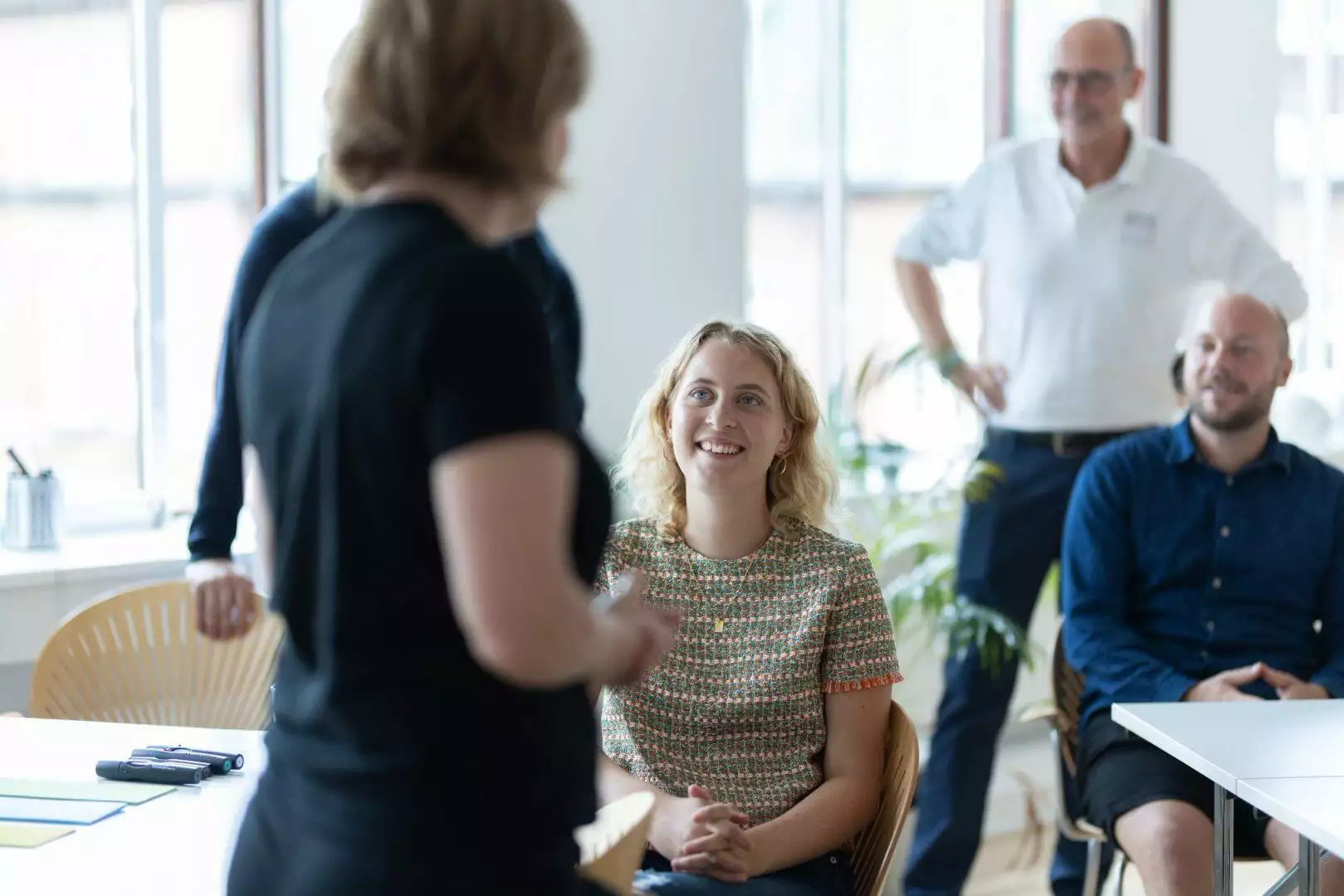 En gruppe mennesker beskæftiget med organisationsudvikling og ledelse, der sidder rundt om et bord i promentums lokaler.