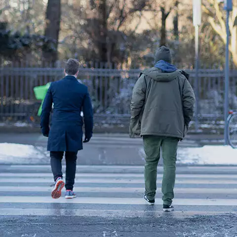 To personer, der øver frisættende dialoger, mens de går over et fodgængerfelt.