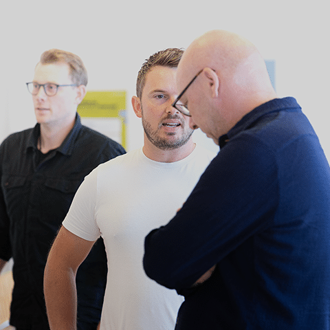 Mikkel Flod Storgaard står og taler med en person iført en hvid skjorte.