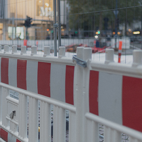 Et byggehegn med røde og hvide striber, der typisk bruges til byggepladser.